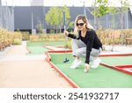 Woman playing mini golf at course. Summer sport and leisure activity