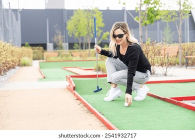 Woman playing mini golf at course. Summer sport and leisure activity - Powered by Shutterstock