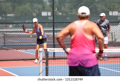 A Woman, Playing In A Mixed Pickleball Tournament, Is About To Serve.