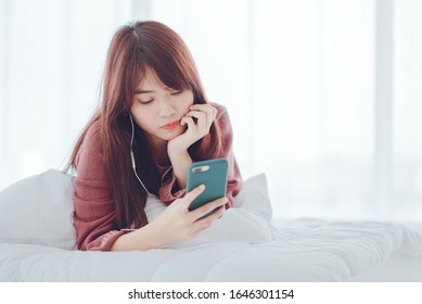 A woman playing on the phone in the bed in the house - Shutterstock ID 1646301154