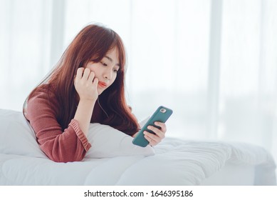 A woman playing on the phone in the bed in the house - Shutterstock ID 1646395186