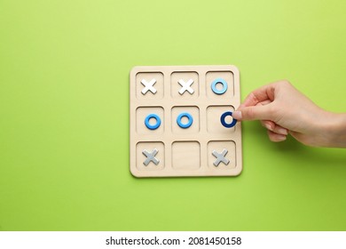 Woman Playing Tic Tac Toe Game On Light Green Background, Top View