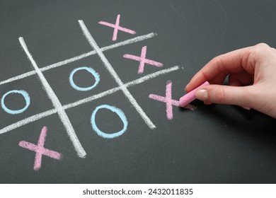 Woman playing tic tac toe on chalkboard, closeup - Powered by Shutterstock