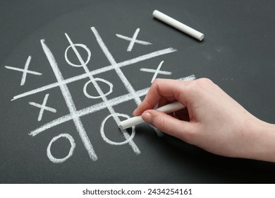 Woman playing tic tac toe on chalkboard, closeup - Powered by Shutterstock