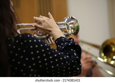 A Woman Playing A Trumpet Musical Instrument In Her Hand Fingers On The Valve Close-up Background Image Of A Musician At Work Back View