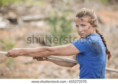 Woman playing tug of war during obstacle course in boot camp