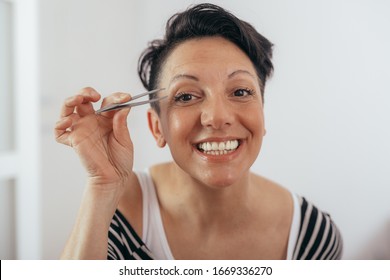 Woman Plucking Her Eyebrows With Tweezer