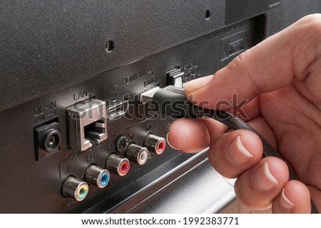 Woman plug an hdmi cable into a tv