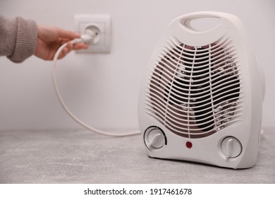 Woman Plug In Modern Electric Fan Heater Indoors, Focus On Device. Space For Text