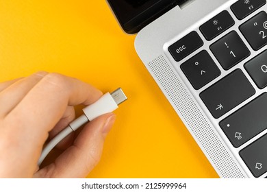 Woman plugging charger in a laptop. Type C charging port. Low battery concept 