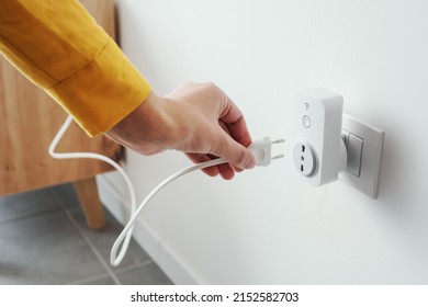 Woman plugging a device into a smart plug, virtual assistant and domotics concept - Shutterstock ID 2152582703