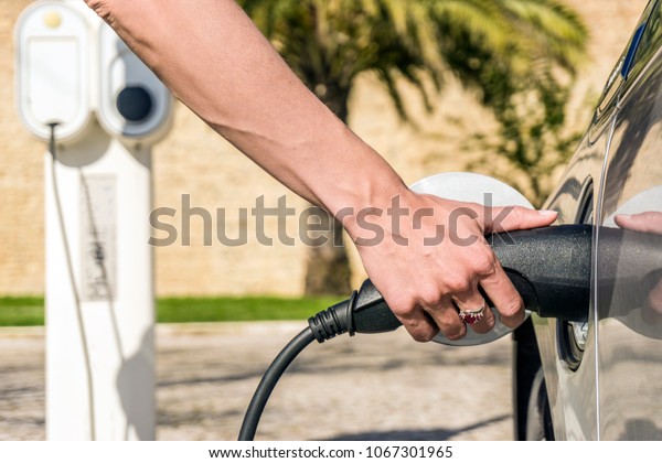 Woman plugs\
electric car to charging\
station