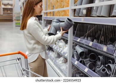 Woman in plumbing store holds gray plastic sewage pipes fittings. - Powered by Shutterstock