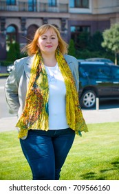A woman of plus size, American or European appearance walks in the city enjoying life. A young lady with excess weight, stylishly dressed in the center of the city
