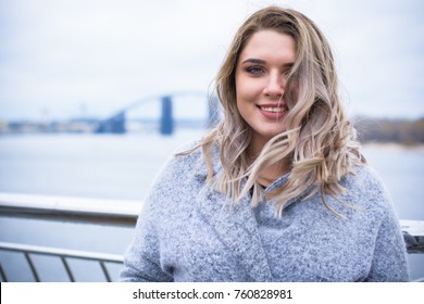 A woman of plus size, American or European appearance walks in the city enjoying life. A young lady with excess weight, stylishly dressed in coat at the center of the city. Natural beauty