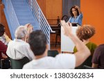 Woman At Podium Chairing Neighborhood Meeting In Community Centre