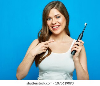 Woman pointing finger on electric toothbrush. Portrait on blue.