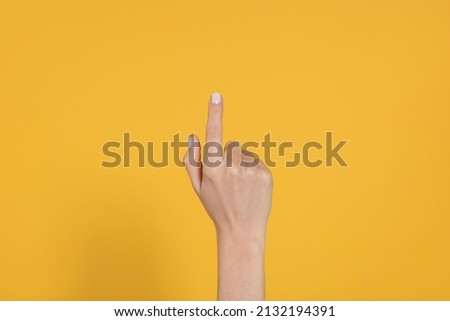 Woman pointing at something against yellow background, closeup on hand