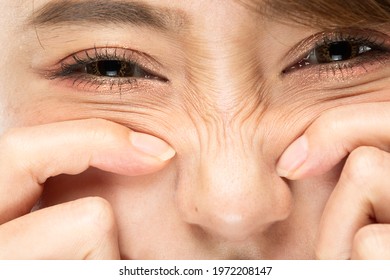 A woman is pointing at the wrinkles on her nose. - Shutterstock ID 1972208147