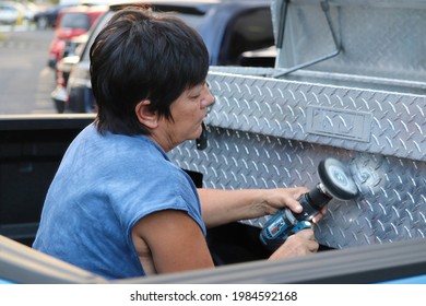 Woman Polishing Aluminum Toolbox With Power Tool While Sitting In Truck Bed