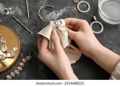 Woman polishing beautiful ring with napkin on grunge background, closeup - Powered by Shutterstock