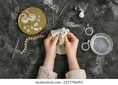 Woman polishing beautiful ring with napkin on grunge background - Powered by Shutterstock