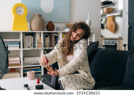 woman polishing nails while relaxing in her apartment