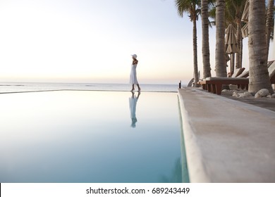Woman at poolside on beach at sunset