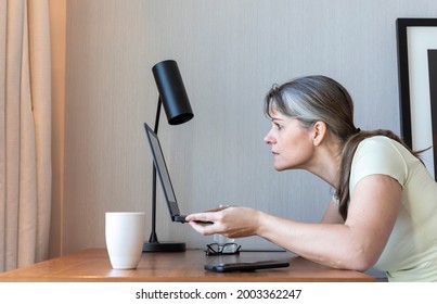 Woman With A Poor Eyesight Working In Her Laptop, Struggling To See