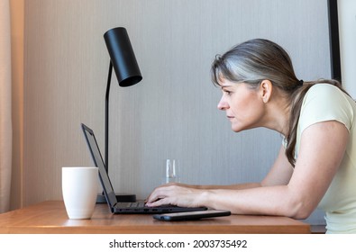 Woman With A Poor Eyesight Working In Her Laptop, Struggling To See