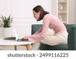 Woman with poor posture using laptop at home