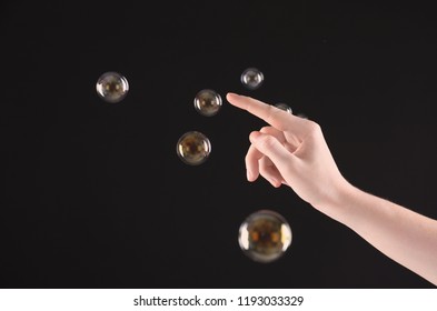 Woman popping soap bubbles on dark background, closeup