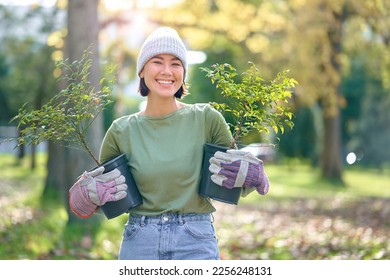 Woman portrait, plant and gardening in a park with trees in nature environment, agriculture or garden. Happy volunteer planting for growth, ecology and sustainability for community on Earth day - Powered by Shutterstock