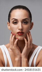Woman, portrait and red lipstick with beauty and manicure, nail polish and cosmetic care for skin on grey background. Face, confidence and bold makeup with hands and color nails for glamour in studio