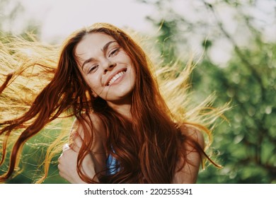 Woman portrait smile happiness catch looks into the camera with a smile with teeth spring flying hair long red, the concept of health and beauty hair sunset - Shutterstock ID 2202555341