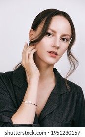 Woman Portrait Wearing Grey Shirt, Air Long Curtain Bangs See-through Fringe In Retro Korean Style. Hand Touches Face, Bracelette On The Arm