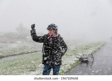 Woman Posing Bravely On An Asphalt Road Through A Wetland Nature Reserve With Bare Trees, Grass And A Snow Storm