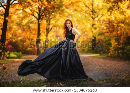 Woman is posing in colourful autumn park at sunset.