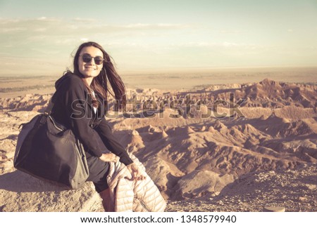 Woman posing and enjoying stunning view and sunset over the Moon Valley in Atacama desert, Chile vacation