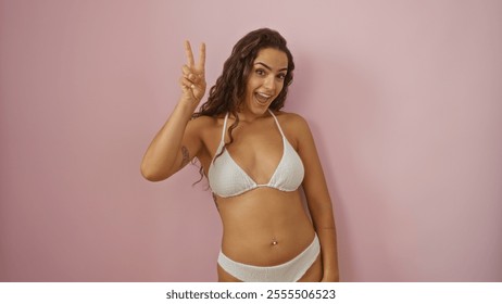 Woman posing over pink background showing peace sign in a bikini - Powered by Shutterstock