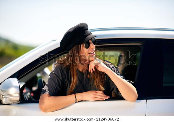 Woman posing\
while leaning on the car\
window.