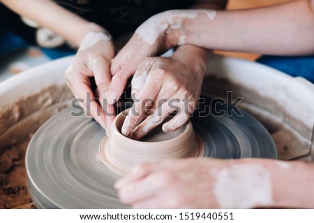 Similar – Young female sitting by table and making clay or ceramic mug