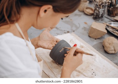 Woman at pottery shop decorating ceramic bowl - Powered by Shutterstock