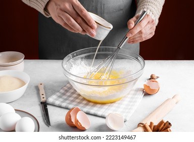 Woman pour milk into a bowl of beaten eggs and flour, mix with whisk on a gray table in the kitchen. Authentic female hands making a dough for homemade pie, Home baking concept, pie crust recipe - Powered by Shutterstock