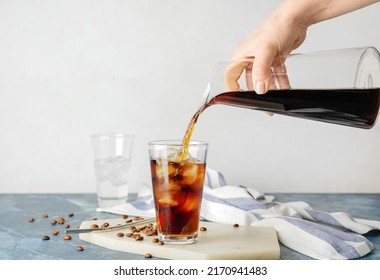 Woman pouring coffee into glass with cold brew on color table against white background - Shutterstock ID 2170941483