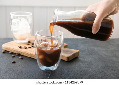 Woman pouring cold brew coffee into glass on table - Shutterstock ID 1134269879