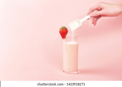 Woman pouring collagen powder or protein in strawberry smoothie or milk. Extra protein intake. Natural beauty and health supplement. Plant or fish based. Copy space.