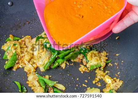 Woman pouring curry powder for cooking  curry fish
