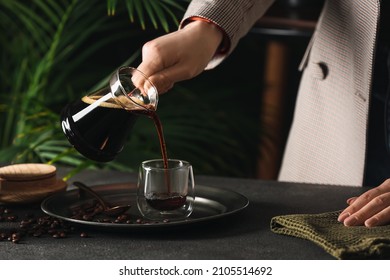 Woman Pouring Delicious Turkish Coffee In Glass Cup At Table