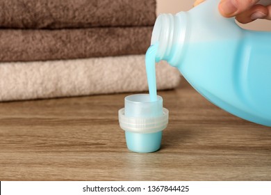 Woman Pouring Detergent Into Cap On Table, Closeup. Laundry Day